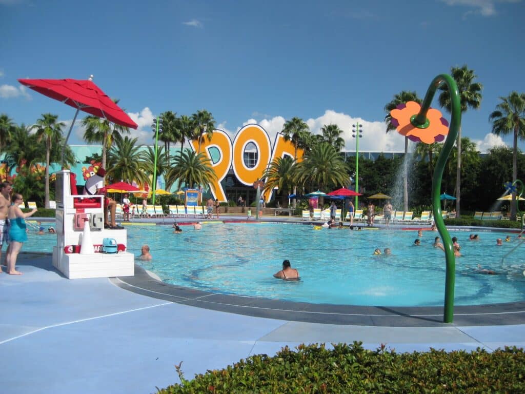 a pool with people in it with Disney's Pop Century Resort in the background