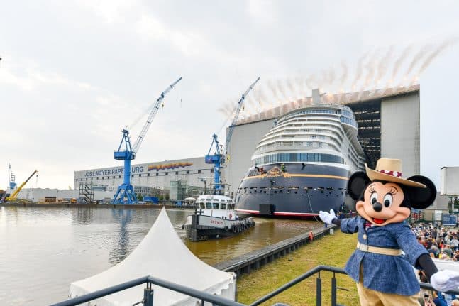 a mickey mouse standing in front of a large ship